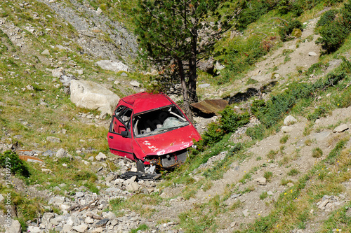 crashed red  car in the ravine