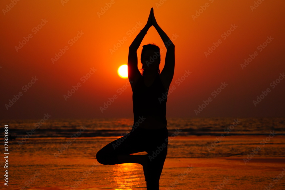 Yoga on the sunset, silhouette of the girl on the sea, yoga pose