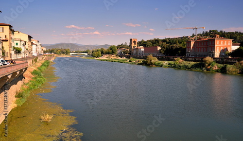 Blick auf die idyllische Wohngegend am Ufer des Arno mit Brücke im Hintergrund