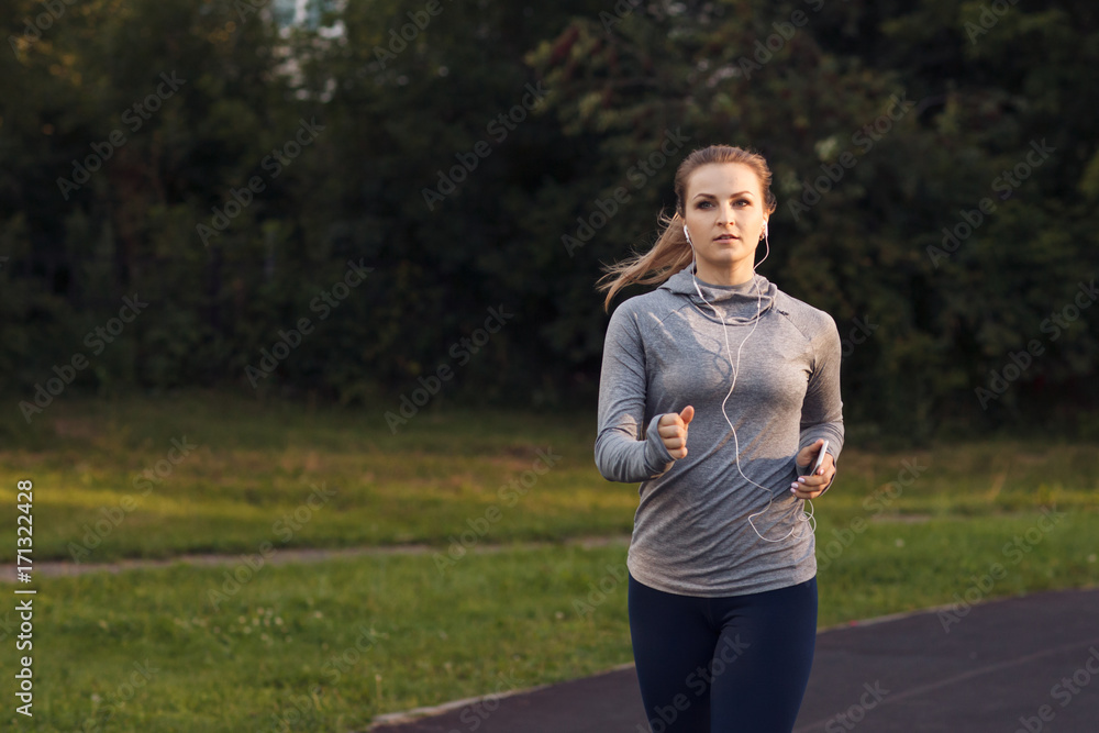 Pretty sporty woman running at park in sunrise Pretty sporty woman running at park in sunrise