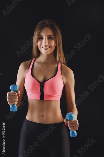 Fitness model woman with dumbbells at studio