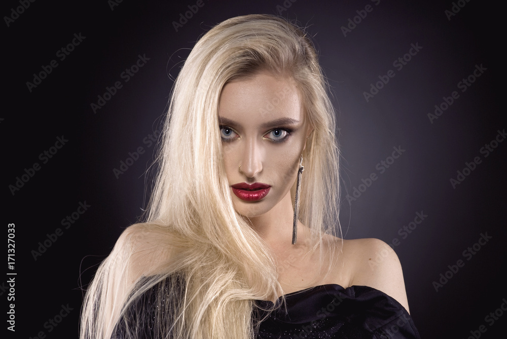 Naklejka premium Beautiful portrait with blonde hair and make up and red lips and jewelry in the studio