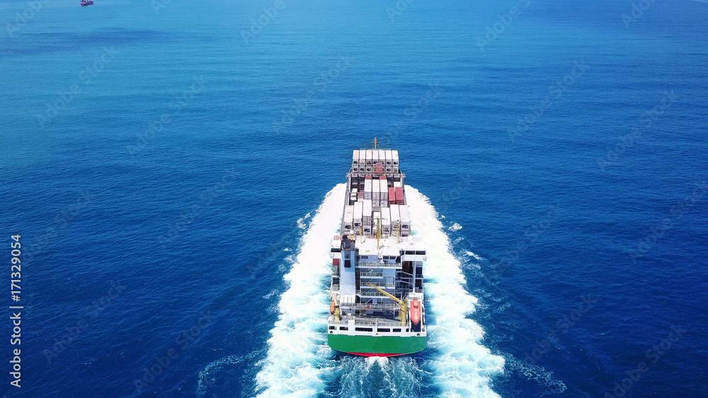 a medum container ship sails on open water fully loaded with containers and cargo