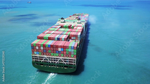Mega huge fully loaded container ship at sea aerial top down