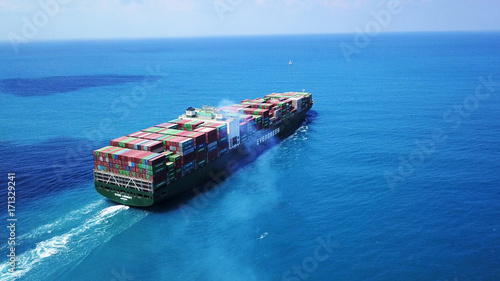 Mega huge fully loaded container ship at sea aerial top down