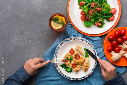 Woman eating healthy food on gray background, top view.