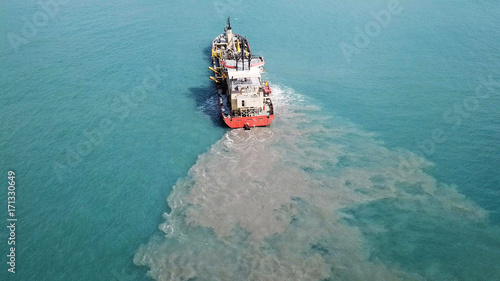 Suction Dredger ship working near the port - with mud, Pollution, brown Muddy water - aerial tip down shot photo