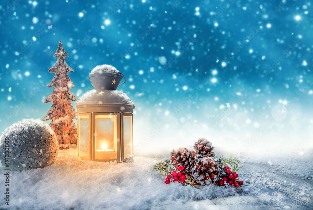 Weihnachtsgesteck mit leuchtender Laterne vor blauen Himmel mit Schneefall  Stock-Foto | Adobe Stock