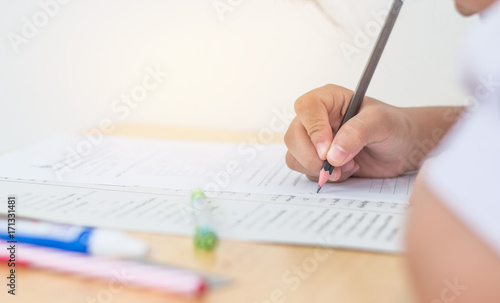 Students using pen writing information on white answer paper in high school, Asian exams room, Tests or examination is assessment intended to measure knowledge, skill, aptitude, Education Concept