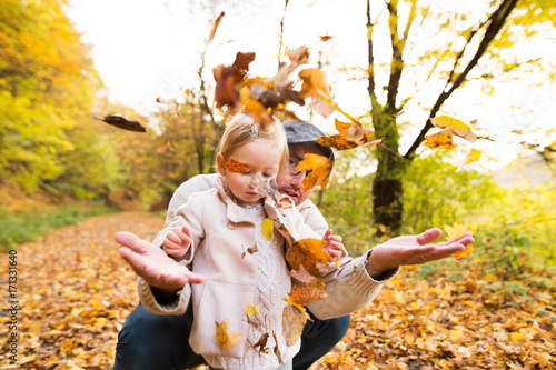 Young father with his daughter in autumn forest.