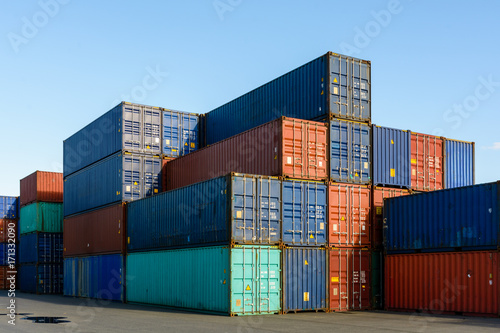 Dozens of multicolored dry cargo containers stacked in an intermodal port terminal.