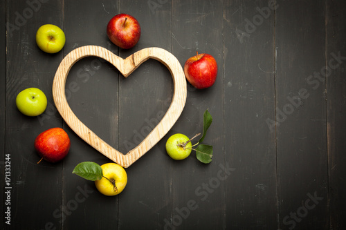 Apples in the heart on a black wooden background