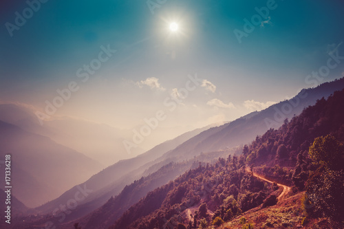 Himalayas landscape. Mountain range with trail in mist and clouds, blue sky with sun in the background. Everest Base Camp road. Trekking in Himalaya mountains, Nepal. Nature landscape. Vintage toning © Goinyk
