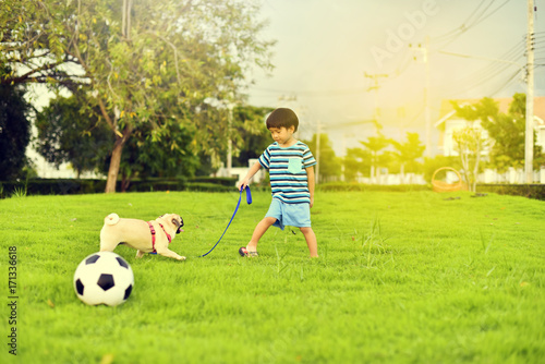 Happy Asian boy playing with his dog in garden 