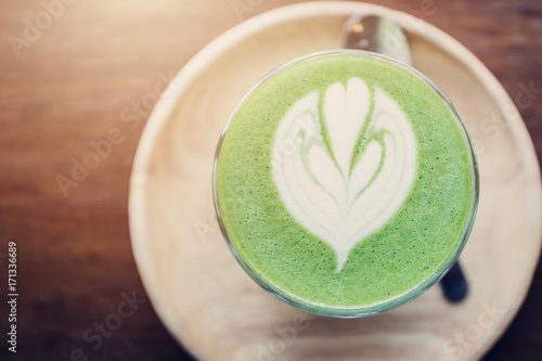 Matcha green tea latte art on wooden table.