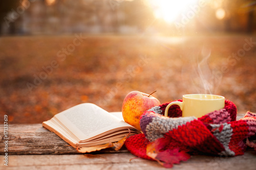 Open book, apple and yellow tea cup with warm scarf
