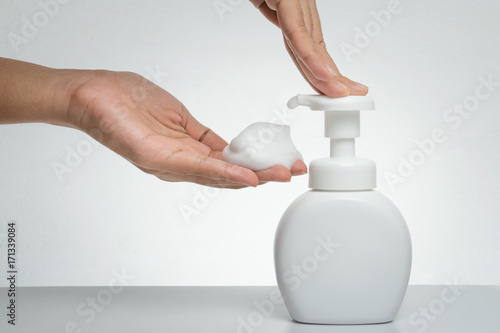 Woman hand press Pure white plastic pump bottle and other hand take cleaner foam