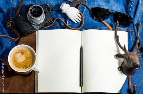 Blank notebook and coffee, camera, sun glasses and vintage prop on the jean shirt. photo