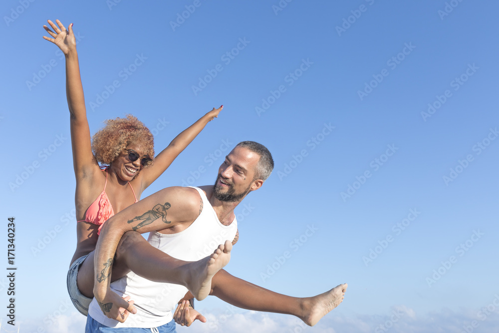 Couple piggy back on the beach in the summer Couple piggy back on the beach in the summer