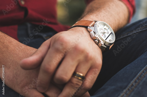 Closeup of young man in casual clothing checking expensive watch