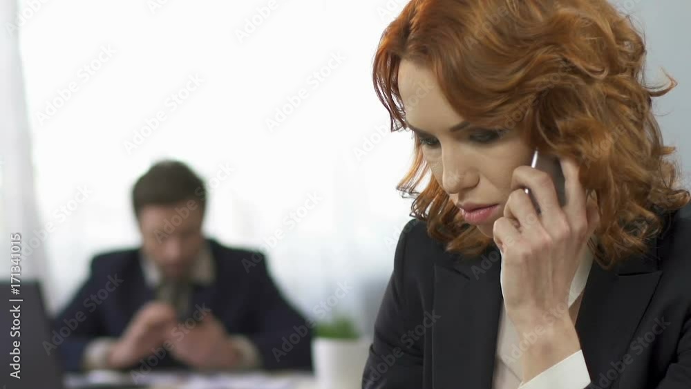 Sad businesswoman talking on the smartphone at workplace, stress, overworking