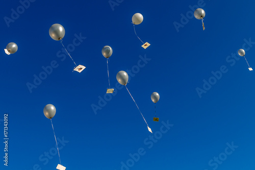 silver balloons going up in the blue sky