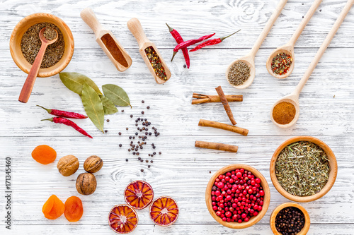 Variety of spices and dry herbs in bowls on wooden kitchen table background top view pattern