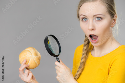 Shocked woman magnifying bun bread roll