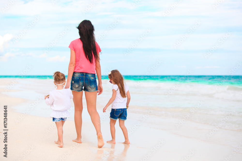 Adorable little girls and young mother on white beach