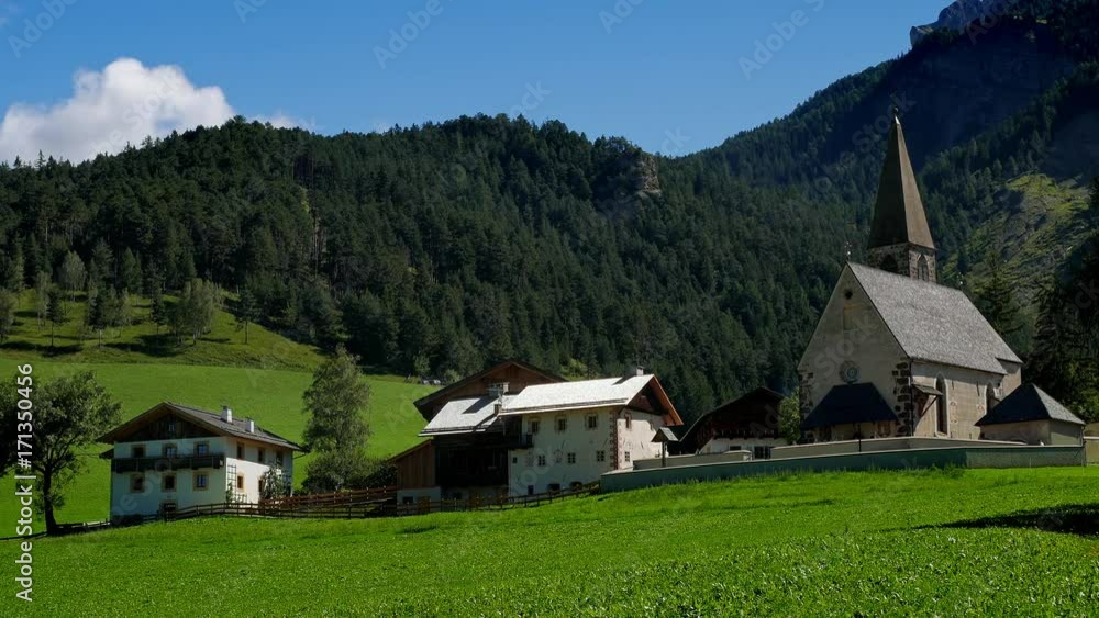 View of the Catholic church and chalets standing on a hill in the highlands View of the Catholic church and chalets standing on a hill in the highlands