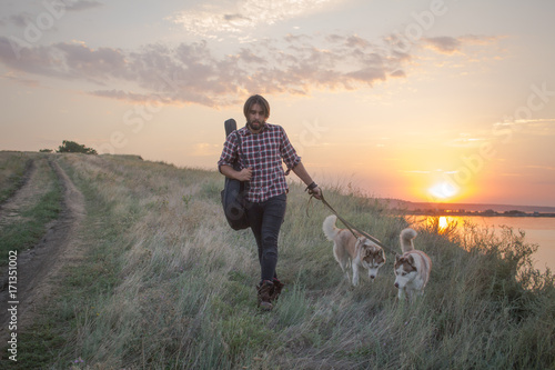 Wallpaper Mural Young bearded and long haired men walk with husky dogs during sunset  Torontodigital.ca