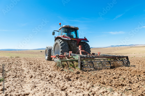 Fotografie agricultural tractor in the foreground with blue sky background.