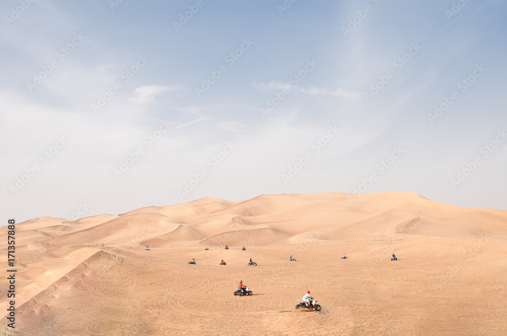 Many Quad bike ATV riders riding at station on red desert hills near Dubai