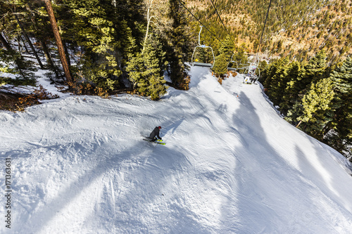 looking down at a skier carving down the run at a ski resort photo