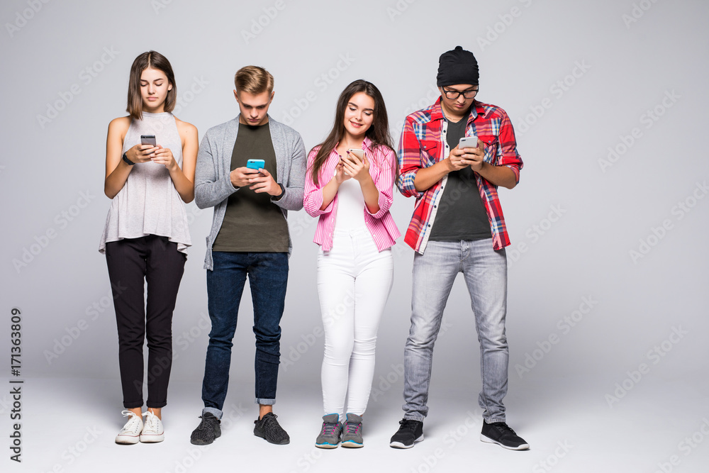 Beautiful young people are using gadgets and smiling, standing against white brick wall Beautiful young people are using gadgets and smiling, standing against white brick wall