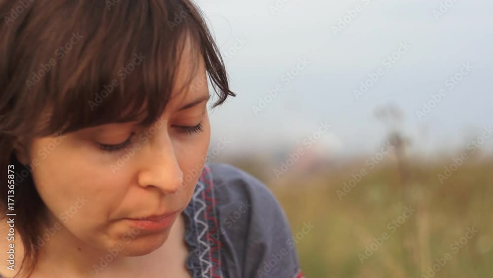 A young woman eats black grapes, a cute little girl bites a sandwich. Family on outside on a picnic on a warm evening at sunset. A young woman eats black grapes, a cute little girl bites a sandwich. Family on outside on a picnic on a warm evening at sunset.