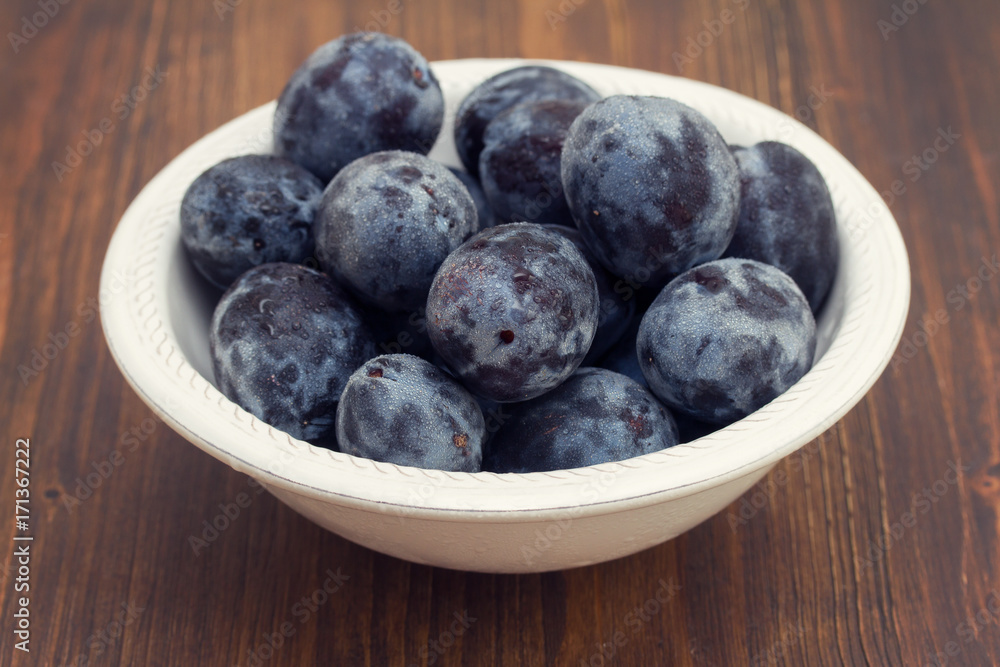 fresh plums in white bowl on wooden background fresh plums in white bowl on wooden background