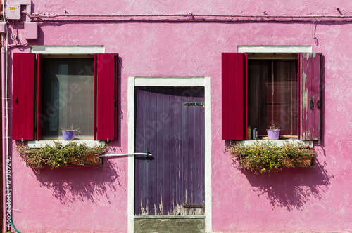 Colorful windows and door with shutters on a pink stucco house