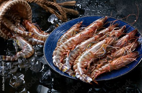 Fresh raw black tiger prawn shrimp with bamboo baskets and ice, shot in dark background photo