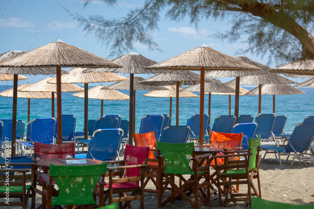 Beach bar with colorful chairs and straws umbrella