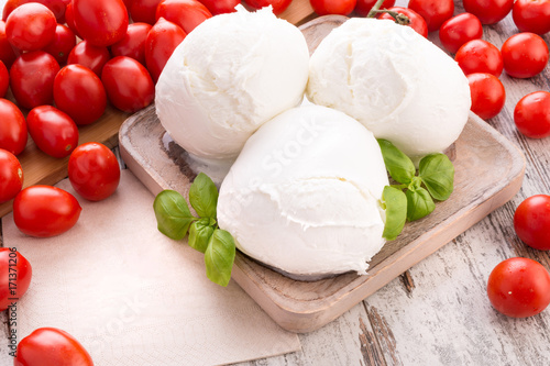 Foto Tre mozzarelle intere di latte di bufala in un piatto di legno su un tavolo con