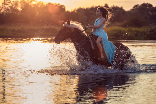 Girl riding horse through river water