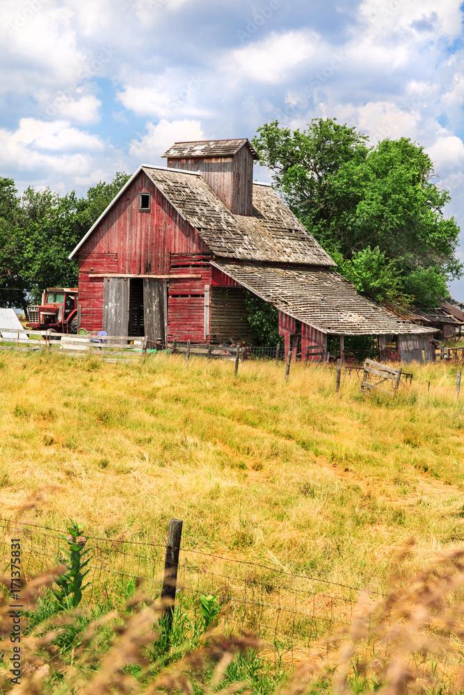 Old red barn on a farm with grassy pasture in the foreground and grees and sky in the background Old red barn on a farm with grassy pasture in the foreground and grees and sky in the background