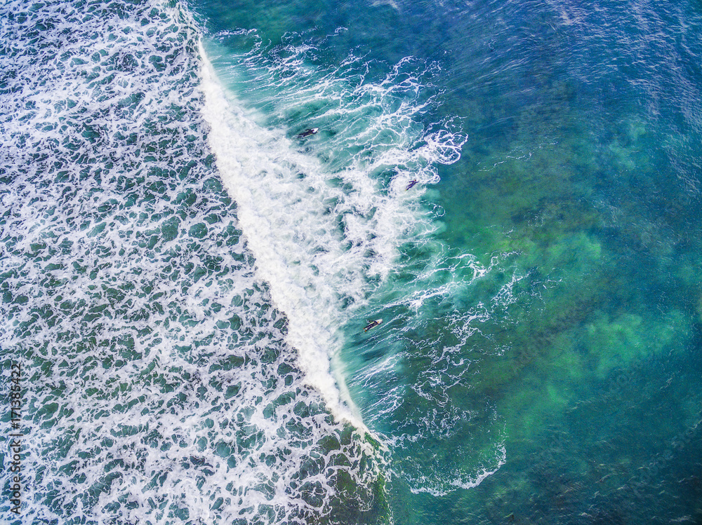 Looking down at surfers in white ocean waves - aerial view