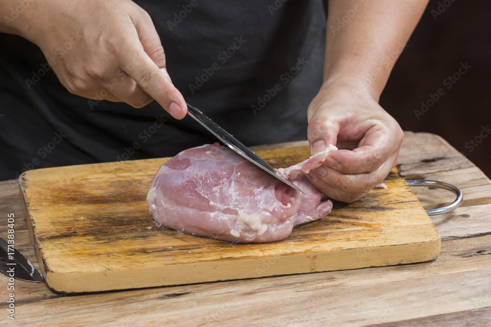 The chef's hands while cutting the pork.