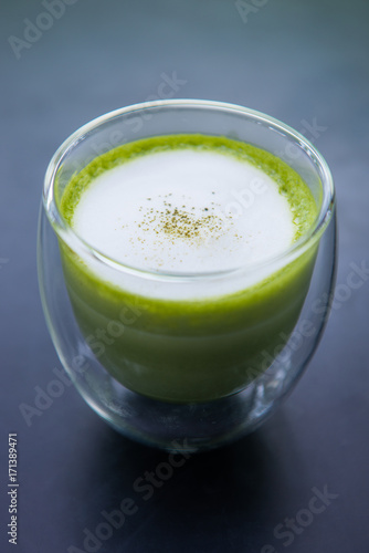 Cup of hot matcha green tea with milk foam.