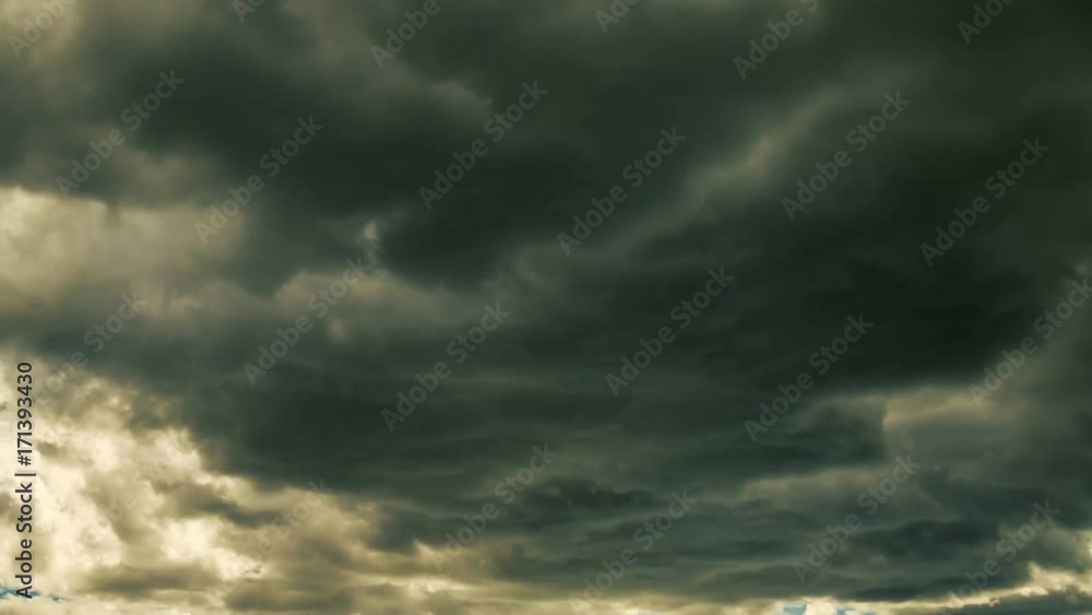 Time-lapse. Fast moving dark clouds before a thunder-storm. The sun breaks through the clouds