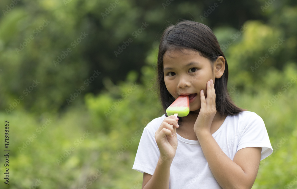 Young asian girl eat an fruit ice cream on the background of the natural at home. She have a hypersensitive teeth during eating. Young asian girl eat an fruit ice cream on the background of the natural at home. She have a hypersensitive teeth during eating.
