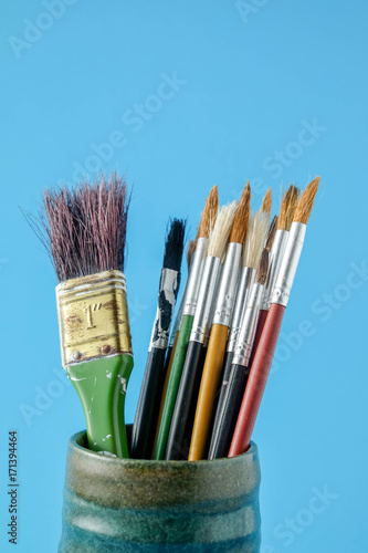 Row of artist paint brushes close up on blue background