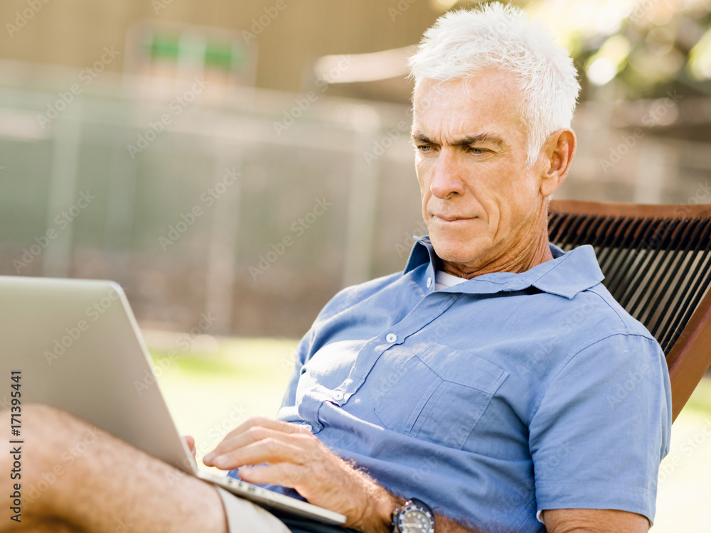 Senior man with notebook sitting in the park Senior man with notebook sitting in the park